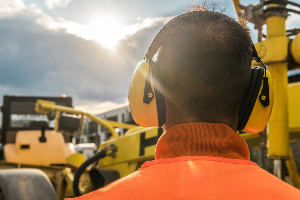 Noise Reduction Construction Equipment. Caucasian Worker with Hearing Protection Headphones.