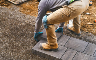 Landscaping paver worker laying paving stones wearing knee pads