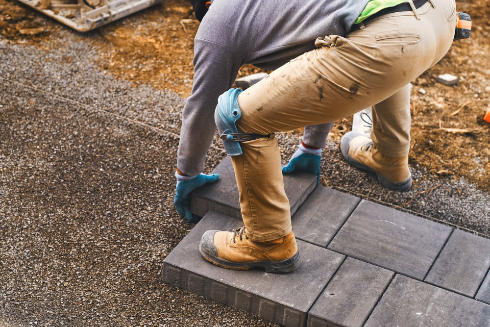 Landscaping paver worker laying paving stones wearing knee pads